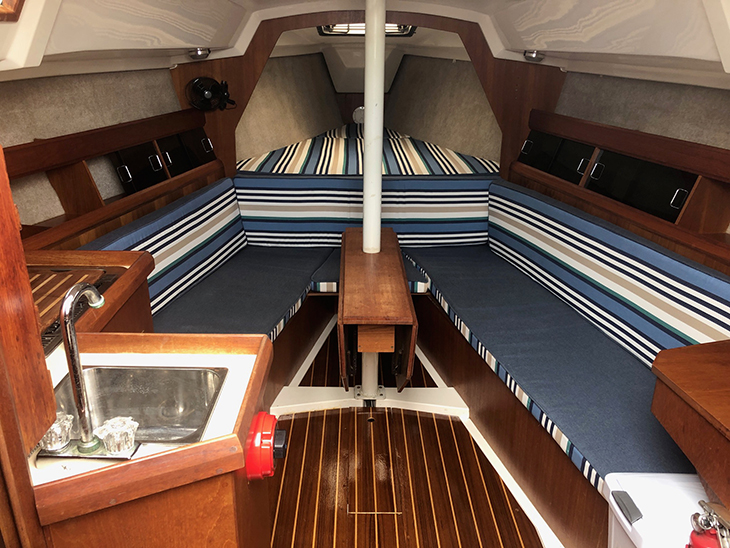 Boat cabin cushions made of blue, tan and white-striped fabric accented with solid blue fabric.